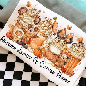 Puede incluir: Una sudadera blanca con un estampado gr&aacute;fico de cuatro caf&eacute;s con nata montada, decorados con hojas de oto&ntilde;o, calabazas y dos personajes de rat&oacute;n. El texto "Autumn Leaves & Coffee Please" est&aacute; impreso en color negro.