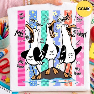 May include: A white t-shirt featuring a graphic of three cartoon seagulls standing on a rock, each with an open beak. The text "MRS. taylor!" is repeated multiple times around the birds. The background consists of vertical stripes in pink, blue, green, and orange with various patterns.