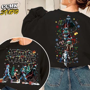 May include: Black sweatshirt featuring a Star Wars holiday design. The front graphic displays Star Wars characters in Santa hats. The back features a Christmas tree design with Darth Vader, Boba Fett, Yoda, and a Stormtrooper.