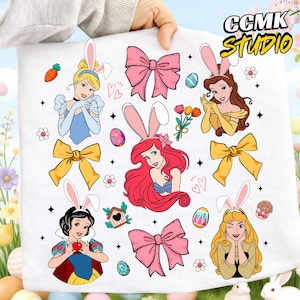 May include: A white fabric featuring cartoon illustrations of Disney princesses wearing bunny ears, surrounded by Easter eggs, bows, and flowers. The image includes the text "CCMK STUDIO" in yellow.