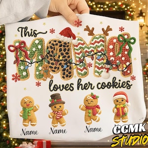Peut inclure: T-shirt blanc sur le thème de Noël avec le texte "This MAMA loves her cookies". Le mot "MAMA" est décoré de motifs et de lumières festives. En dessous, quatre bonhommes en pain d'épices avec des étiquettes nominatives personnalisables.