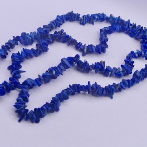 May include: A long strand of blue lapis lazuli gemstone chips, strung together to form a necklace.