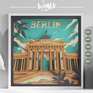 Może przedstawiać: Papierowy wycinany wzór Bramy Brandenburskiej w Berlinie, Niemcy. Wzór znajduje się w ramie z turkusowym tłem i brązowymi i czarnymi akcentami. Tekst "BERLIN" znajduje się na górze wzoru.