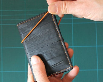 Trifold wallet with orange elastic band and coin pocket made from recycled inner bike tubes.