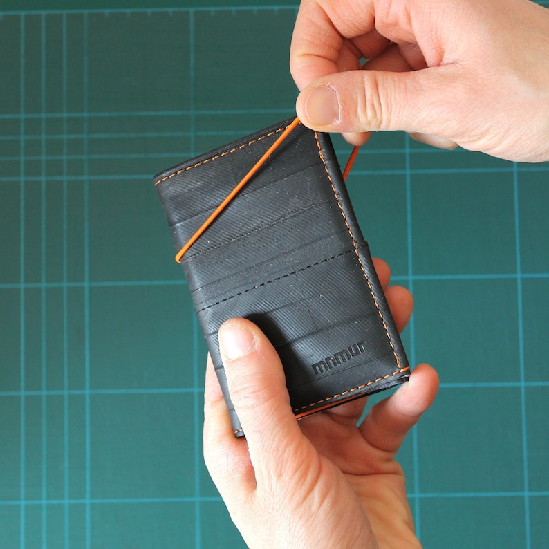 Pequeña cartera de hombre en negro y naranja con banda elástica y monedero, hecha a mano con cámaras de bicicleta recicladas. imagen 1