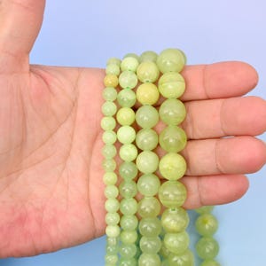 May include: A strand of light green jade beads in various sizes. The beads are round and smooth, and they are strung on a clear thread.