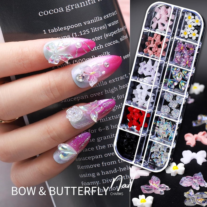 Op de afbeelding: Een set nail art bedels in een doorzichtige plastic organizer, met verschillende vormen zoals strikken, vlinders en bloemen. De afbeelding toont ook een hand met verzorgde nagels versierd met vergelijkbare bedels en strass-steentjes. De tekst "BOW & BUTTERFLY" is zichtbaar.