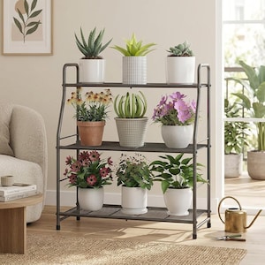 May include: A three-tier metal plant stand with a dark gray finish, featuring a rectangular frame and wire mesh shelves. The stand holds nine potted plants of various sizes, including succulents, flowering plants, and green foliage in assorted pots.