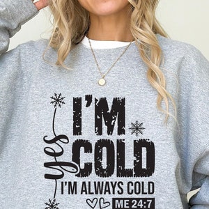 Może przedstawiać: Szara bluza z czarnym nadrukiem, który mówi "Tak, jestem zimno, zawsze jestem zimno, ja 24:7" ze śnieżynkami i sercami.