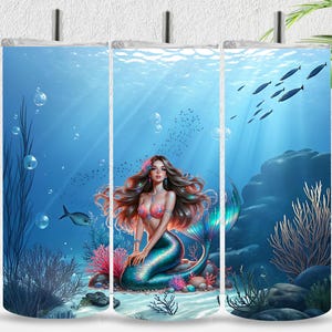 Könnte beinhalten: Eine Meerjungfrau mit langen roten Haaren und einem blauen Schwanz sitzt auf einem Felsen im Meer. Das Meer ist blau und es schwimmen Fische um sie herum. Der Hintergrund ist ein Korallenriff mit Seegras und Blasen.