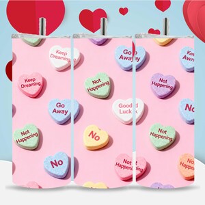 Pode incluir: Um copo com fundo rosa decorado com doces em forma de coração. Os doces têm várias cores pastel e frases como "Keep Dreaming" e "Go Away". Perfeito para o Dia dos Namorados.
