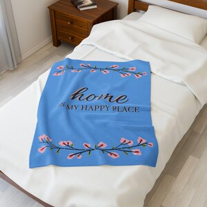 Puede incluir: Una manta de tiro azul con un diseño floral y el texto "home is my happy place".