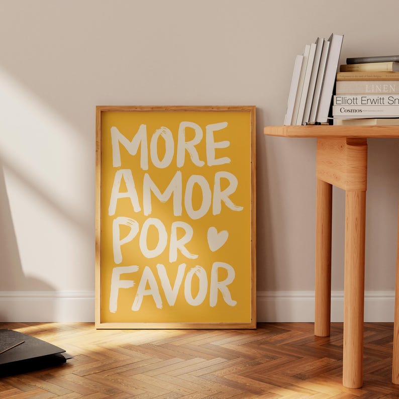 Peut inclure: Une affiche encadr&eacute;e jaune avec les mots "MORE AMOR POR FAVOR" en blanc, avec un symbole de c&oelig;ur. L'affiche est dans un cadre en bois et est affich&eacute;e sur un mur. L'affiche est un objet d&eacute;coratif.