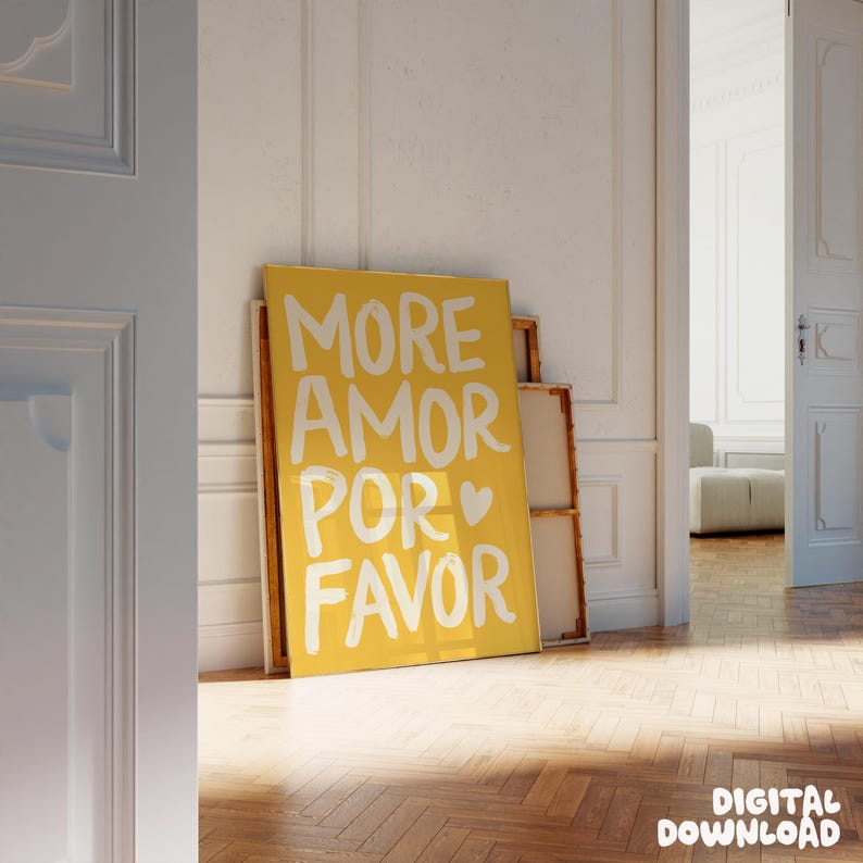 Peut inclure: Une affiche jaune avec l'inscription blanche "MORE AMOR POR FAVOR". L'affiche est appuy&eacute;e contre un mur blanc, avec un parquet au premier plan. Les mots se traduisent par "Plus d'amour s'il vous pla&icirc;t".