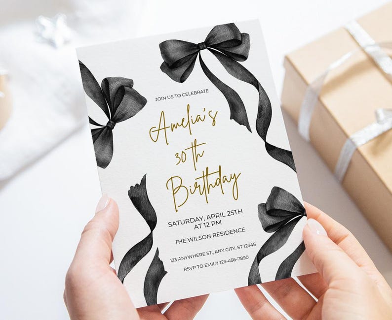 May include: A white invitation with black watercolor bows and gold text. The text reads "Join us to celebrate Amelia's 30th Birthday. Saturday, April 25th at 12 PM. The Wilson Residence. 123 Anywhere St, Any City, ST 12345. RSVP to Emily 123-456-7890."