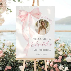 Può includere: Un cartello bianco su un cavalletto di legno con un fiocco e nastri rosa ad acquerello. Il cartello recita "Benvenuti al 16° compleanno di Elisabeth" con una foto di una giovane donna. La data "14 aprile 20XX" è in basso.