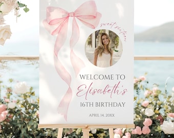 May include: A white sign on a wooden easel with a pink watercolor bow and ribbons. The sign reads "Welcome to Elisabeth's 16th Birthday" with a photo of a young woman. The date "April 14, 20XX" is at the bottom.