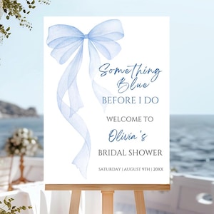 Op de afbeelding: Een wit bord met een blauwe aquarel strik en de tekst "Something Blue Before I Do"  "Welcome to Olivia's Bridal Shower"  "Saturday | August 9th | 20XX"