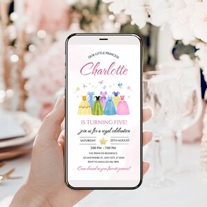 K&ouml;nnte beinhalten: Ein Smartphone zeigt eine Einladung zum Geburtstag mit Prinzessinnen-Motiv. Die Einladung lautet "Unsere kleine Prinzessin Charlotte wird f&uuml;nf!" und enth&auml;lt Eventdetails. Das Design zeigt Aquarellkleider und Schmetterlinge in Pastellfarben.
