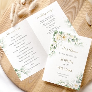 Op de afbeelding: Elegant trouwprogramma met bloemen- en groenaccenten. Het programma bevat de details van de ceremonie en de informatie over de bruiloftsgasten. De voorkant leest "Welkom bij de bruiloft van Sophia en William".