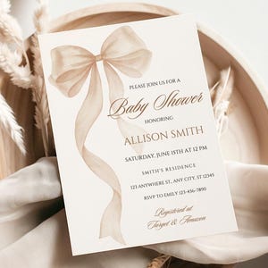 Puede incluir: Una invitación a un baby shower con un diseño de lazo y cinta en acuarela beige y marrón. La invitación incluye el texto "Baby Shower" y los detalles de la fiesta de Allison Smith, incluyendo fecha, hora y lugar.
