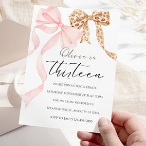 Könnte beinhalten: Eine weiße Einladungskarte mit rosa und braunen Aquarell-Schleifen. Der Text lautet "Olivia ist dreizehn" und enthält Details für eine Geburtstagsfeier.