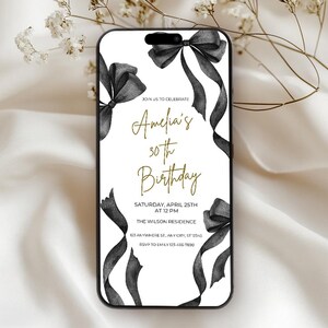 May include: A white invitation with black ribbon bows and gold text. The text reads "Join us to celebrate Amelia's 30th Birthday. Saturday, April 25th at 12 PM. The Wilson Residence 123 Anywhere St, Any City, ST 12345. RSVP to Emily 123-456-7890."