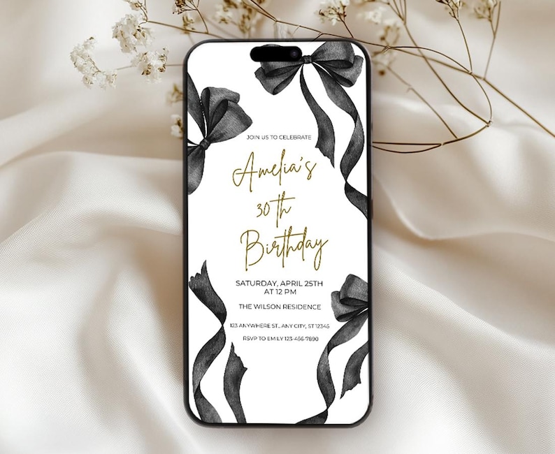 May include: A white invitation with black ribbon bows and gold text. The text reads "Join us to celebrate Amelia's 30th Birthday. Saturday, April 25th at 12 PM. The Wilson Residence 123 Anywhere St, Any City, ST 12345. RSVP to Emily 123-456-7890."