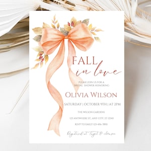 May include: A white invitation card with the text "FALL in love" and details for a bridal shower. It features a watercolor illustration of a peach-colored bow with flowing ribbons and autumn foliage.