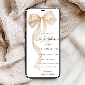 May include: A mobile phone shows a baby shower invitation with a beige and brown watercolour bow and ribbon design. The invitation includes details for Allison Smith's baby shower, such as the date, time, and location.