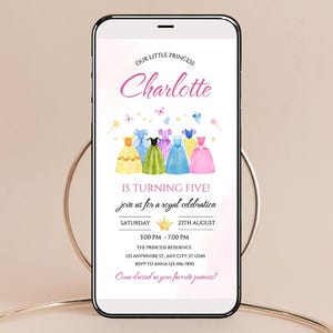K&ouml;nnte beinhalten: Ein Smartphone zeigt eine Geburtstagseinladung mit Prinzessinnen-Thema. Die Einladung enth&auml;lt den Namen "Charlotte" in rosa Schrift, Illustrationen von bunten Prinzessinnenkleidern und Veranstaltungsdetails. Der Text lautet "Is Turning Five!" und "Come dressed as your favorite princess!"