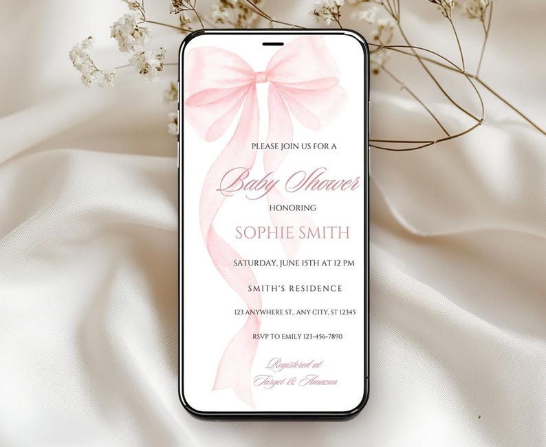 May include: A pink baby shower invitation with a watercolor bow on a white background. The invitation includes the text "Please join us for a Baby Shower honoring Sophie Smith, Saturday, June 15th at 12 PM, Smith's Residence, 123 Anywhere St. Any City, ST 12345, RSVP to Emily 123-456-7890, Registered at Target & Amazon."