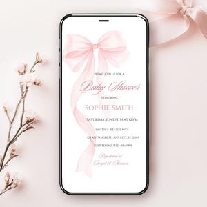 May include: A pink baby shower invitation with a watercolor bow on a white background. The invitation text reads "Please join us for a Baby Shower honoring Sophie Smith, Saturday, June 15th at 12 PM, Smith's Residence, 123 Anywhere St. Any City, ST 12345, RSVP to Emily 123-456-7890, Registered at Target & Amazon."