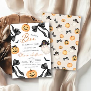 Könnte beinhalten: Halloween-Babyparty-Einladung mit Aquarelldesign. Die Einladung zeigt einen Geist mit Hexenhut, Kürbissen und schwarzen Schleifen. Der Text lautet "A Little Boo is Almost Due!" und enthält Eventdetails.