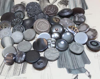 May include: A collection of vintage gray buttons in various shapes and sizes. The buttons are made of different materials, including metal and plastic, and feature a range of textures and designs. Some buttons have intricate patterns and embellishments.