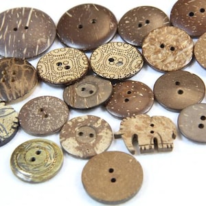 May include: A collection of brown coconut shell buttons with various designs, including a flower, an elephant, and geometric patterns.
