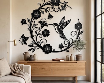 Peut inclure: Une décoration murale en métal noir représentant un colibri en vol entouré d'un arrangement incurvé de fleurs, de feuilles et de vignes tourbillonnantes. Le design est complexe avec des détails découpés sur l'oiseau et les pétales floraux.