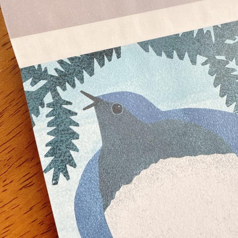 May include: A close-up of a printed illustration featuring a bluebird with a white chest, singing. The bird is set against a light blue background with a stylized tree branch. The top of the print has a light purple and white border.