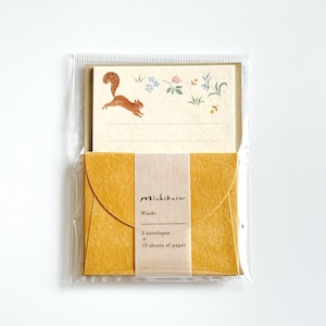 Pode incluir: Um conjunto de papelaria numa bolsa de plástico transparente contendo dez folhas de papel creme com uma ilustração em aguarela de um esquilo e flores, e cinco envelopes amarelo-mostarda presos por uma faixa Michikusa Washi.