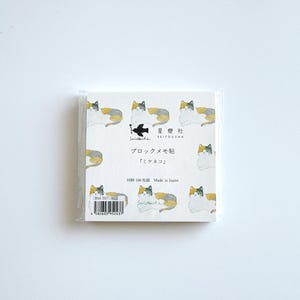 May include: A square notepad featuring a repeating pattern of calico cats in white, grey, and yellow. The notepad is packaged in clear plastic. Text on the notepad reads "Seitousha" and "Made in Japan."