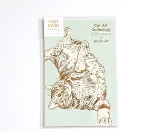 May include: A postcard with a gold illustration of a cat on a pale green background. The cat is depicted upside down. Text on the card reads "POST CARD" and "Cat Art Collection".