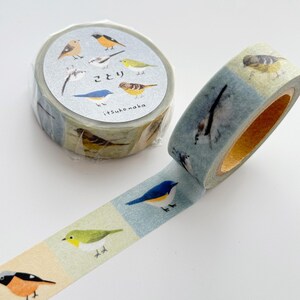 May include: Decorative washi tape featuring colorful bird illustrations. The tape roll is wrapped in clear plastic, with the tape itself displaying various bird species on a light blue and beige background. The tape is unrolled, showcasing the repeating bird pattern.