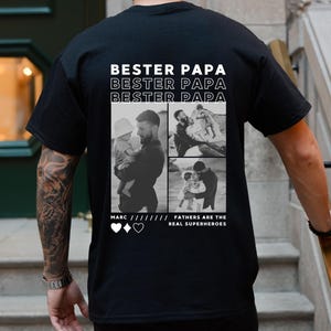 May include: Black t-shirt with the text "Bester Papa" repeated three times. The shirt features a collage of three black and white photos of a father with his children. The text "Fathers are the real superheroes" is below the photos.