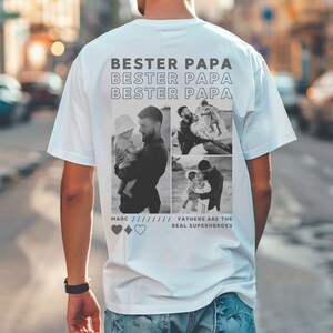 May include: White t-shirt with the text "Bester Papa" repeated three times. The shirt features three black and white photos of a father with his children. The text "Fathers are the real superheroes" is printed below the photos.