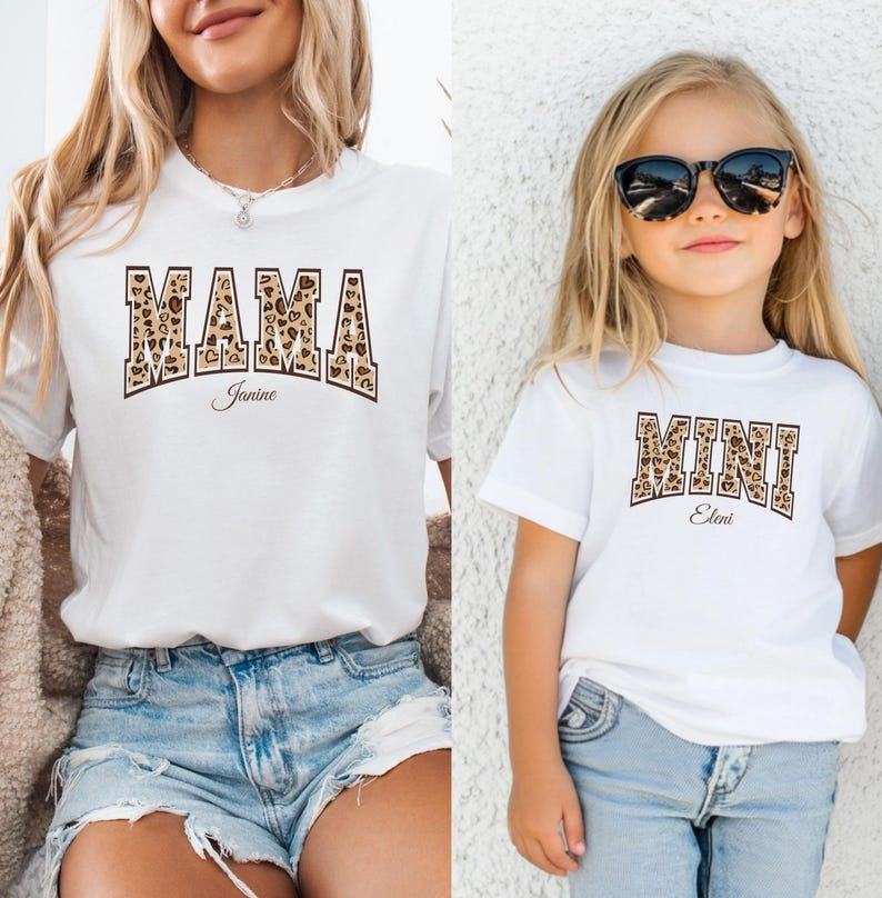 May include: White t-shirts with a leopard print design. The larger shirt says "MAMA Janine" and the smaller shirt says "MINI Eleni".