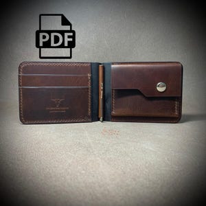 Könnte beinhalten: Geöffnete braune Ledergeldbörse mit Kartenfächern und einem Druckknopfverschluss. Die Geldbörse hat einen Stifthalter und ein Logo eines Bullenkopfes. Das PDF-Symbol befindet sich oben links.