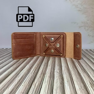 Könnte beinhalten: Geöffnete braune Ledergeldbörse mit mehreren Kartenfächern und einem Münzfach, das mit Druckknöpfen gesichert ist. Die Geldbörse ist offen dargestellt und zeigt ihr Innendesign. Das PDF-Symbol befindet sich oben links.