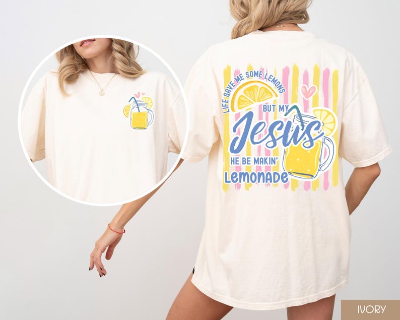 May include: Ivory-colored t-shirt with a lemonade graphic on the front and back. The front features a small lemonade illustration. The back has a larger design with the text "Life gave me some lemons but my Jesus he be makin' lemonade."