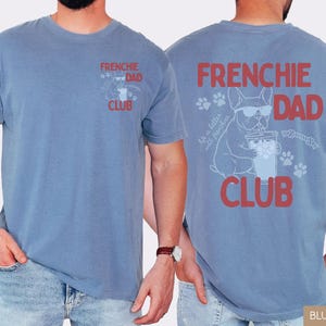 May include: Blue jean colored t-shirt with "FRENCHIE DAD CLUB" printed in red. The back features a graphic of a French Bulldog wearing sunglasses, drinking from a cup, and the text "Life is better with frenchies."
