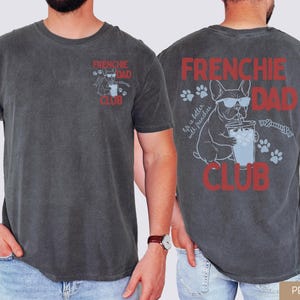 May include: Pepper-colored t-shirt with "FRENCHIE DAD CLUB" in red text. The front features a small graphic of a French Bulldog with sunglasses. The back displays a larger graphic of the dog with a drink and paw prints.